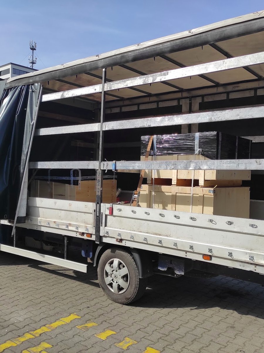 Otwarta plandeka busa Bee-Trans z załadowanymi kartonami na paletach